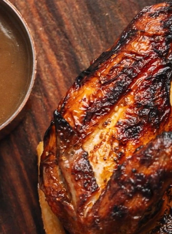 Charcoal grilled chicken with gravy on a wooden board
